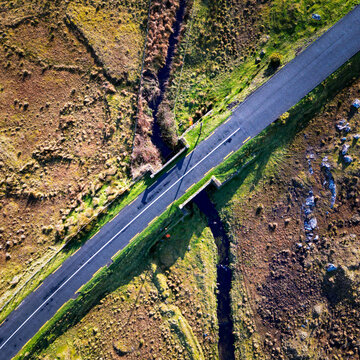 Aerial view of a road crossing a stone bridge over a stream in the rural landscape of Howth, Dublin, County Dublin, Ireland.