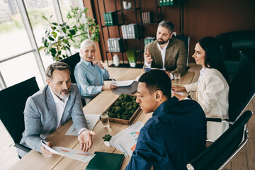 Group of professionals engaged in a teamwork strategy meeting in a modern workspace with diverse...