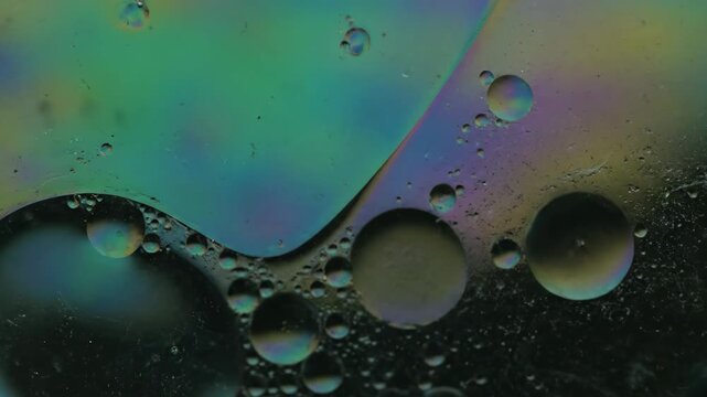 Abstract iridescent soap film surface with small water droplets and rainbow colors reflecting light and creating a pattern with a science and technology theme