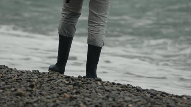 Rubber boots, stormy sea, walking along a rocky beach during a heavy storm, protected from the crashing waves.