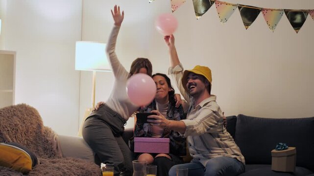 Joyful friends taking selfies at birthday party