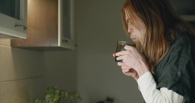 Caucasian man drink hot water in evening. Single male is drinking tea at kitchen at home. 4K 10-bit