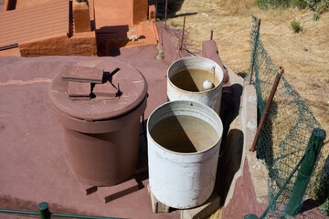 Naklejka premium Water storage tanks and barrels sit on a rooftop terrace in the rural mountain village of Artenara in Gran Canaria.