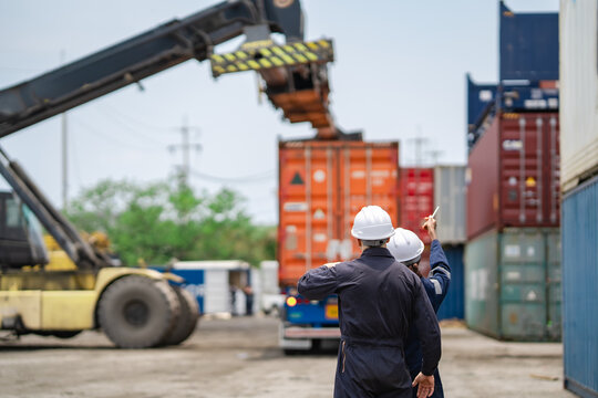 Industrial logistics team observing container handling equipment during freight loading process. Port workers coordinate transportation, cargo movement, and international shipping.