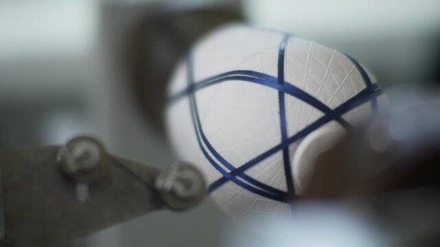 Extreme macro shot focusing on dark carbon fiber strands being precisely wrapped around a textured white mandrel during an industrial filament winding process.