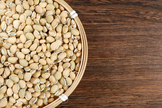 Fresh hyacinth beans in a woven bamboo basket on wooden surface