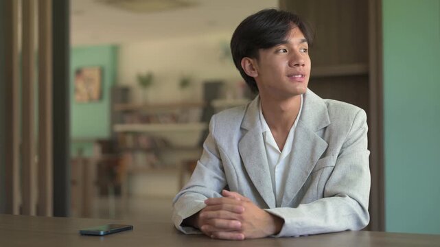 Portrait of young person from Southeast Asia Thai Isan sitting and looking through window smiling