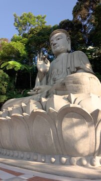 The iconic stone Buddha statue at Chin Swee Caves Temple in Genting Highlands sits gracefully on a lotus pedestal, surrounded by lush mountain rainforest.