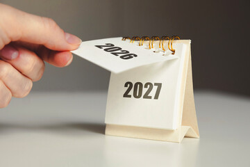 Turning the page from 2026 to 2027 – New Year calendar concept with hand and desk flip calendar   © Annamorphosis