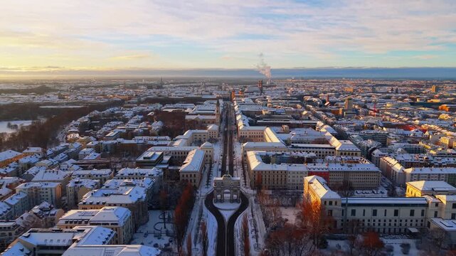Drone footage of Siegestor triumphal arch and Ludwigstrasse in Munich. Snowy winter landscape, historic buildings and urban panorama of Bavaria city center.