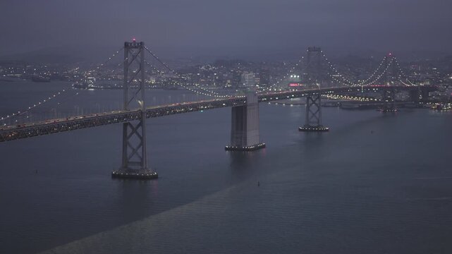 Sparkling San Francisco Bay Bridge Suspension Towers at Dusk With Overcast Sky - Aerial Shot