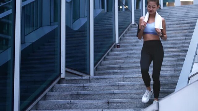 Athelte sporty woman activewear jogging down the stairs workout outdoors in the city park wearing sporty shoes and fitness outfit with fitness watch tracker for training, exercise and cardio fitness