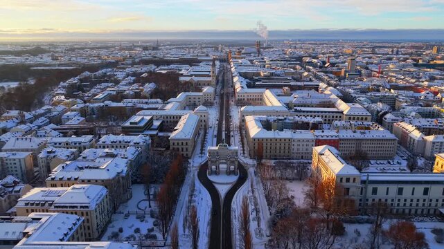 Aerial winter view of Siegestor near LMU Munich at sunrise, showing snowy streets, historic architecture and the cold seasonal mood of the Maxvorstadt landmark boulevard