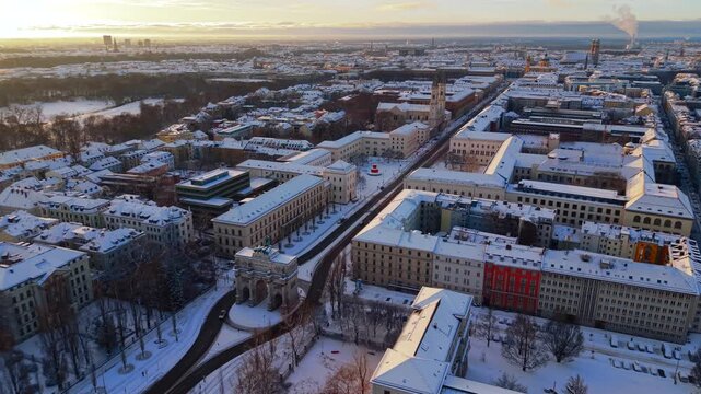 Snowy morning aerial of Professor-Huber-Platz and Siegestor, highlighting Munichs winter charm, historic architecture and soft golden hour light