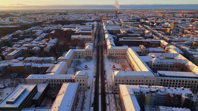 Aerial drone view of Siegestor Victory Gate in Munich Germany in winter. Snow covered streets, historic architecture and Ludwig Maximilian University create a cinematic city panorama.