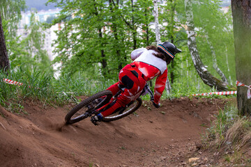 Obraz premium Rear view woman downhill racer riding turn of forest trail