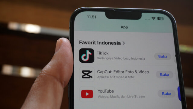 Purwokerto, Indonesia - 17 June 2026: Hand holding an iPhone showing a list of popular apps in Indonesia, including TikTok, CapCut, and YouTube.