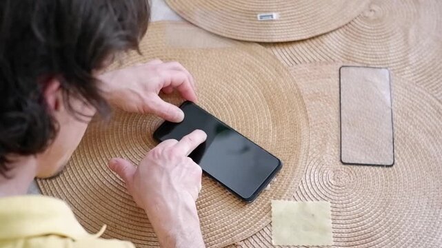 Male hands carefully applying a tempered glass screen protector on a modern mobile phone display