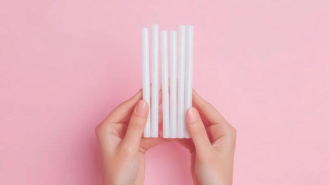 A close-up of a human hand holding a clear plastic measuring ruler against a pink background, displaying centimeter and millimeter increments.