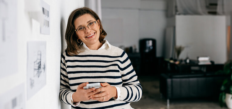 The woman takes a work break with her phone in a design studio beside wall drawings
