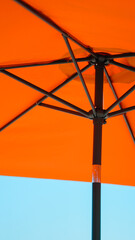 Naklejka premium Underside of an orange beach umbrella showing the frame structure