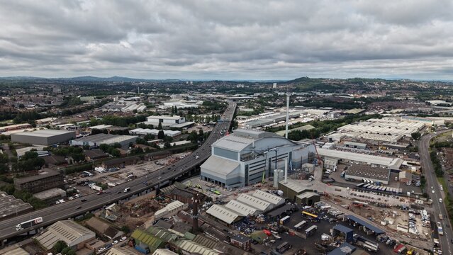 High-altitude drone photograph overlooking Birmingham, England, featuring the M5 motorway, industrial facilities, commercial warehouses, residential neighborhoods and urban infrastructure beneath dram