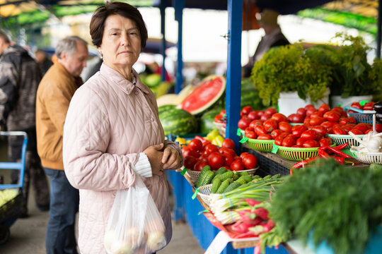 elderly woman buys vegetables at an open market