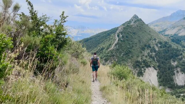 Randonneur qui avance sur un sentier face &agrave; une montagne devant lui