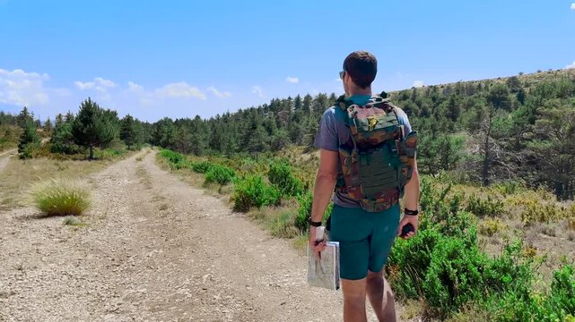 Randonneur qui avance sur un sentier de montage et regarde sa carte