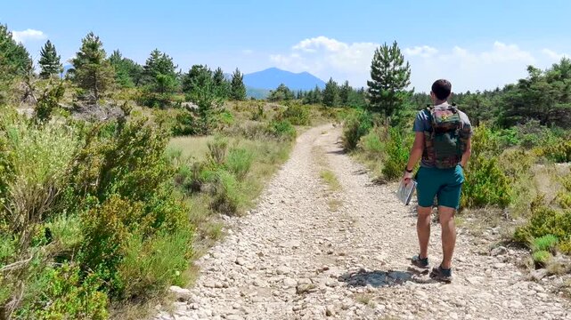 Randonneur qui avance sur un sentier de montage et regarde sa carte