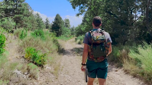 Randonneur qui avance sur un sentier de montage forestier et regarde sa carte