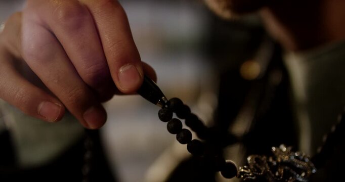 A man holds a string of black beads in his hand