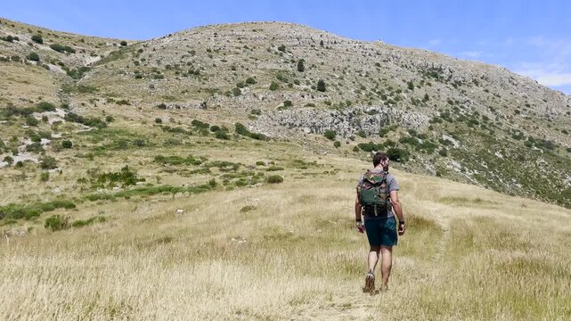 Randonneur qui avance sur un sentier de montage en direction du sommet du Mont Chiran
