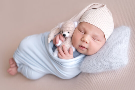 Newborn baby sleeps soundly on light beige surface. Professional newborn photoshoot.