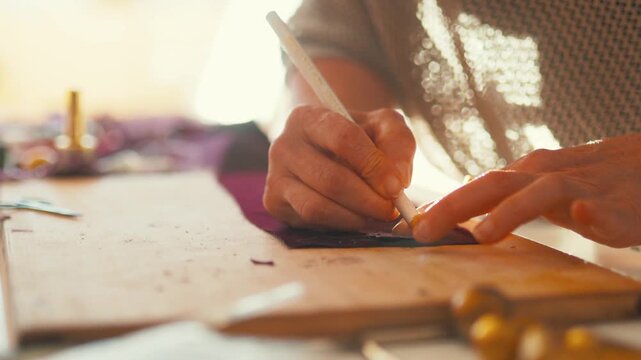 Crafting a design on fabric in a workshop setting with hands and tools focused on details