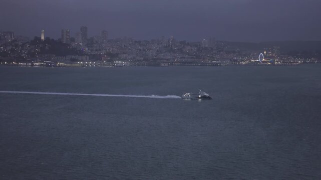 Passenger Ferry Crossing San Francisco Bay at Dusk With Sparkling Lights In Background - Aerial Shot