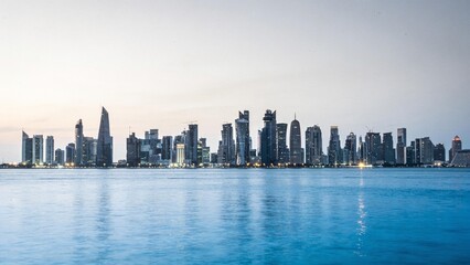 Fototapeta premium A serene evening cityscape with a calm body of water reflects the urban skyline at dusk.