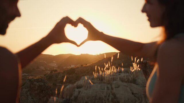 Couple sharing a heartfelt moment, hands forming a heart shape against a stunning golden hour sunset, symbolizing eternal love and romance, perfect for wedding planning and romantic getaways.