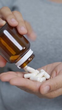 close up woman hand holding a medicine, with pours the pills out of the medicine bottle. Stop drug use Taking Medication Caring for the health care medical concept. capsule.	
