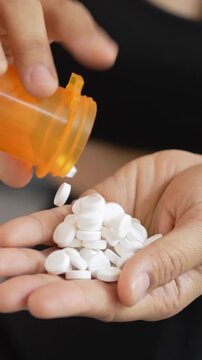 close up woman hand holding a medicine, with pours the pills out of the yellow orange medicine bottle. Stop drug use Taking Medication Caring for the health care medical concept.	