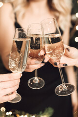 Close up of women hands clinking champagne glasses during a festive holiday party. © Olga