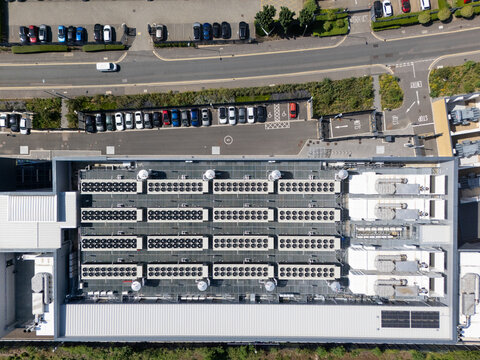Aerial view of a data centre roof featuring rows of industrial cooling units and ventilation systems, situated in an urban industrial area in London, England, United Kingdom.
