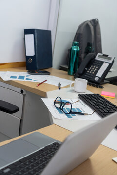 Office desk with laptop, glasses, and financial reports