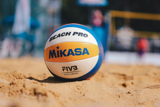 Official Mikasa beach volleyball ball on the yellow sand court close up, blurred background