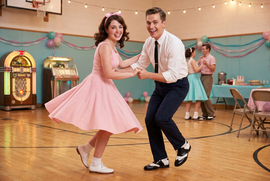 Young couple dancing joyfully at retro-themed sock hop event  