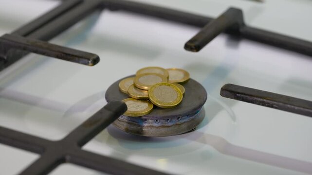 High gas costs. Conceptual video showing a gas stove burner igniting with a pile of euro coins on it, symbolizing the increasing price of gas, high energy costs, and the economic impact