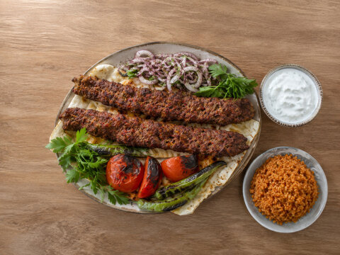 Kebab turco a la parrilla servido con bulgur, yogur, tomate y cebolla.