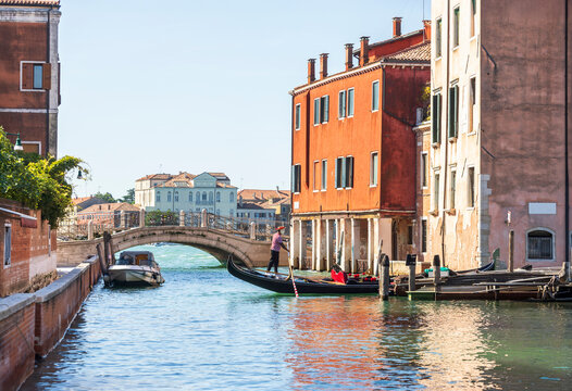 Traditional Gondola on a Quiet Venetian Canal with Historic Bridge in Venice, Italy