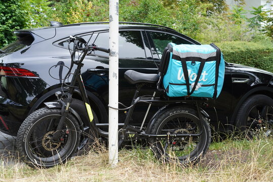 Elektrisches Fatbike von Koolux (Typ X7) mit einer hellblauen Wolt-Liefertasche f&uuml;r den steht angeschlossen an einer Stra&szlig;e im Stadtgebiet, Berlin, 01.07.2026