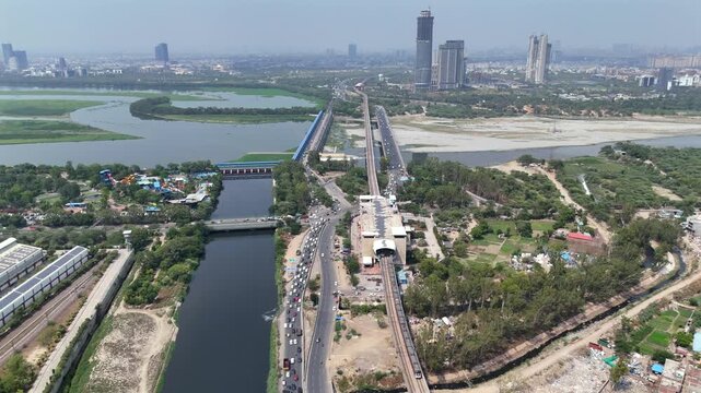 Aerial drone view of Kalindi Kunj Bridge over Yamuna River with Delhi Metro and Noida skyline, India